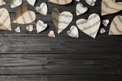 Paper hearts with music notes and space for text on wooden background, flat lay