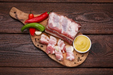 Photo of Pieces of pork fatback with chilli pepper and sauce on wooden table, top view