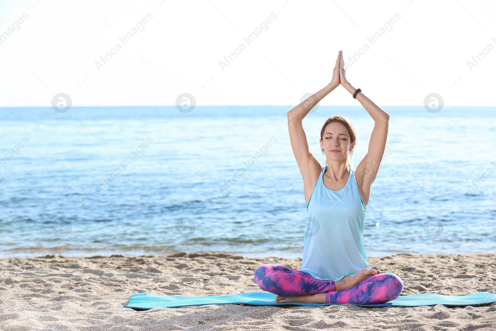 Photo of Young woman doing yoga exercises on beach in morning