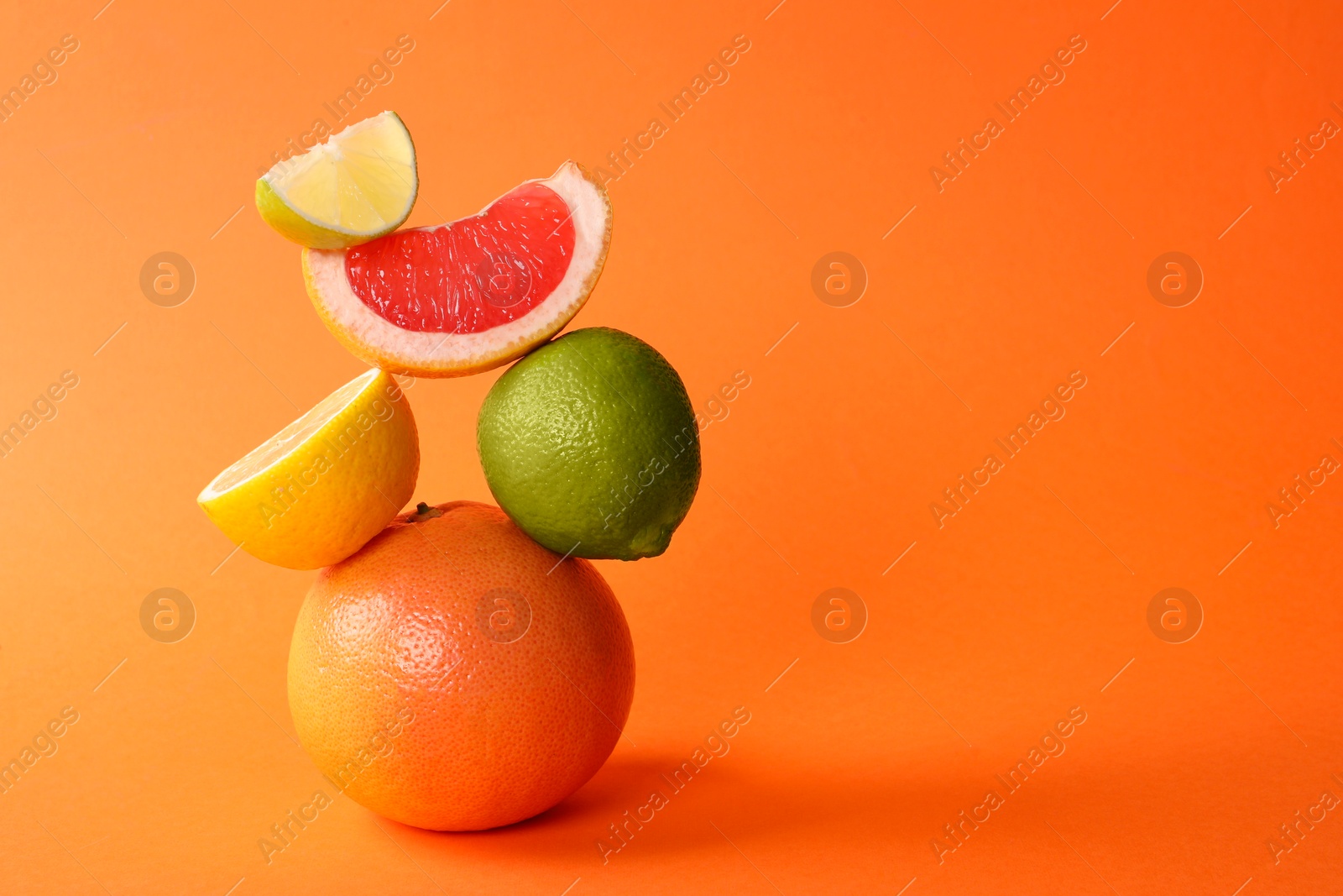 Photo of Fresh ripe citrus fruits on orange background, space for text