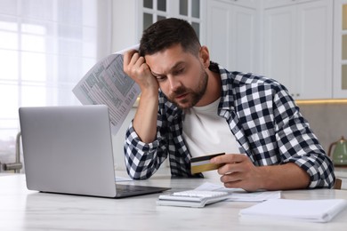 Photo of Man with credit card using laptop for paying taxes online at home