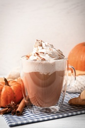 Delicious pumpkin latte with whipped cream on table, closeup