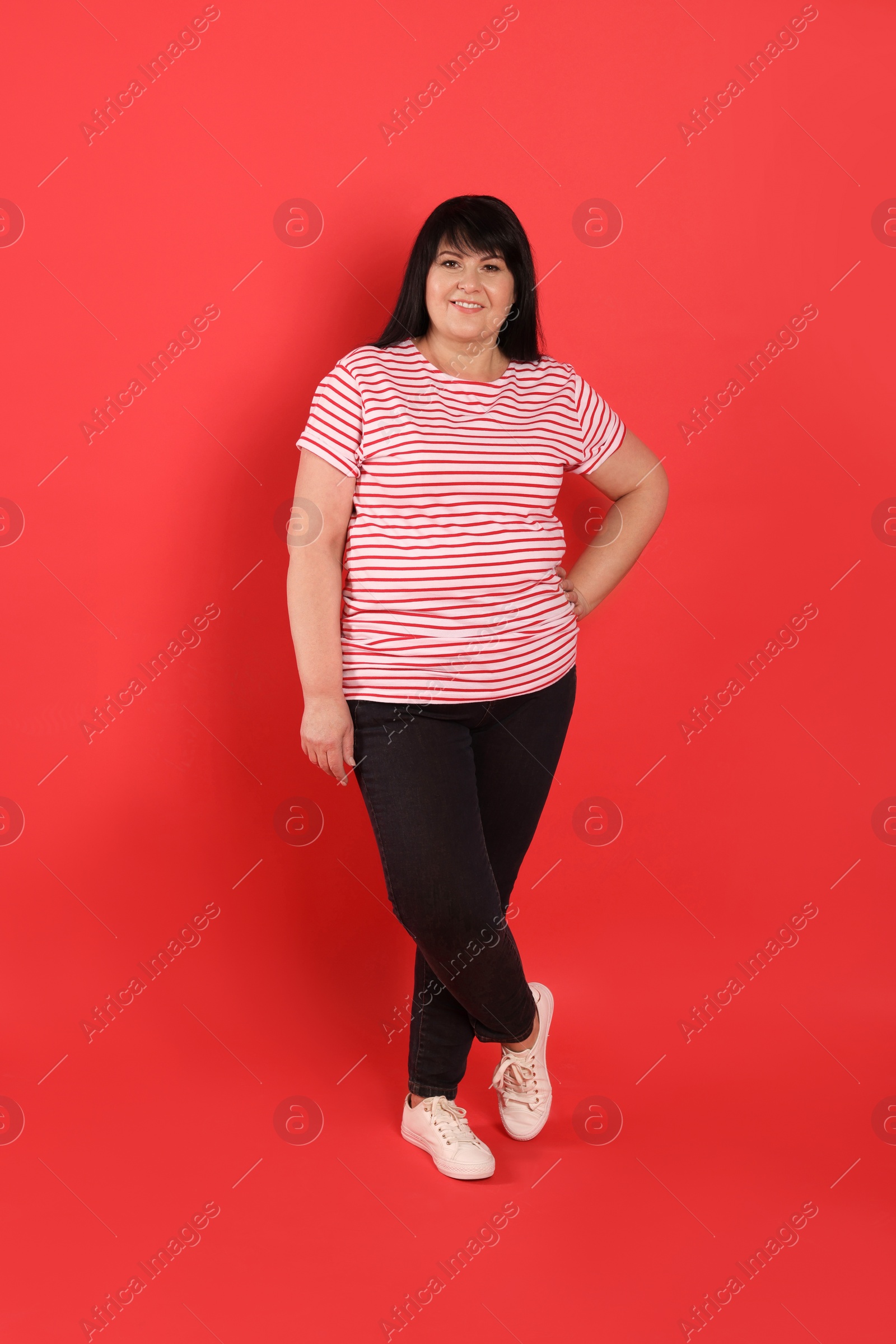 Photo of Beautiful overweight mature woman with charming smile on red background