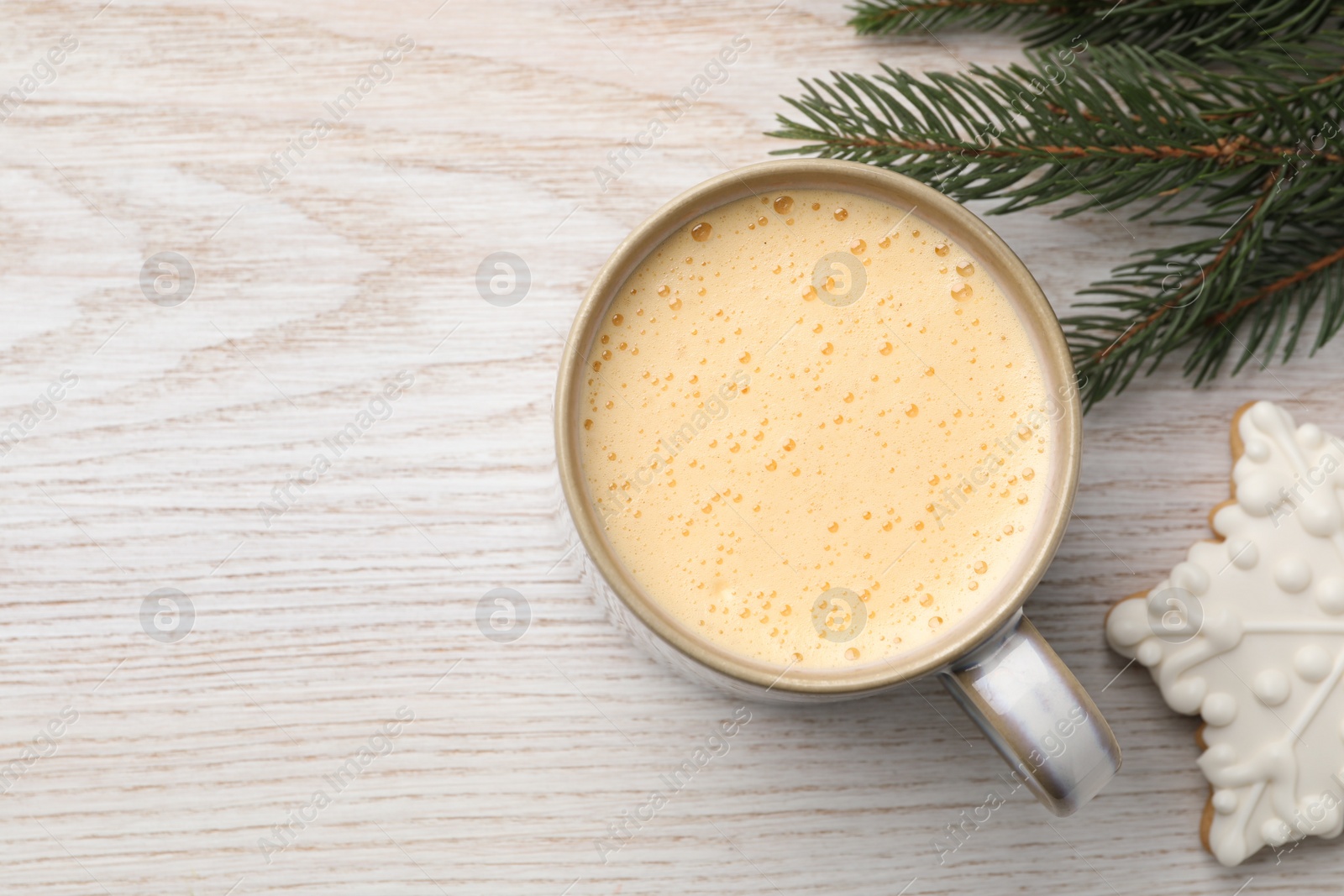 Photo of Cup of delicious eggnog, fir branch and cookie on wooden table, flat lay. Space for text