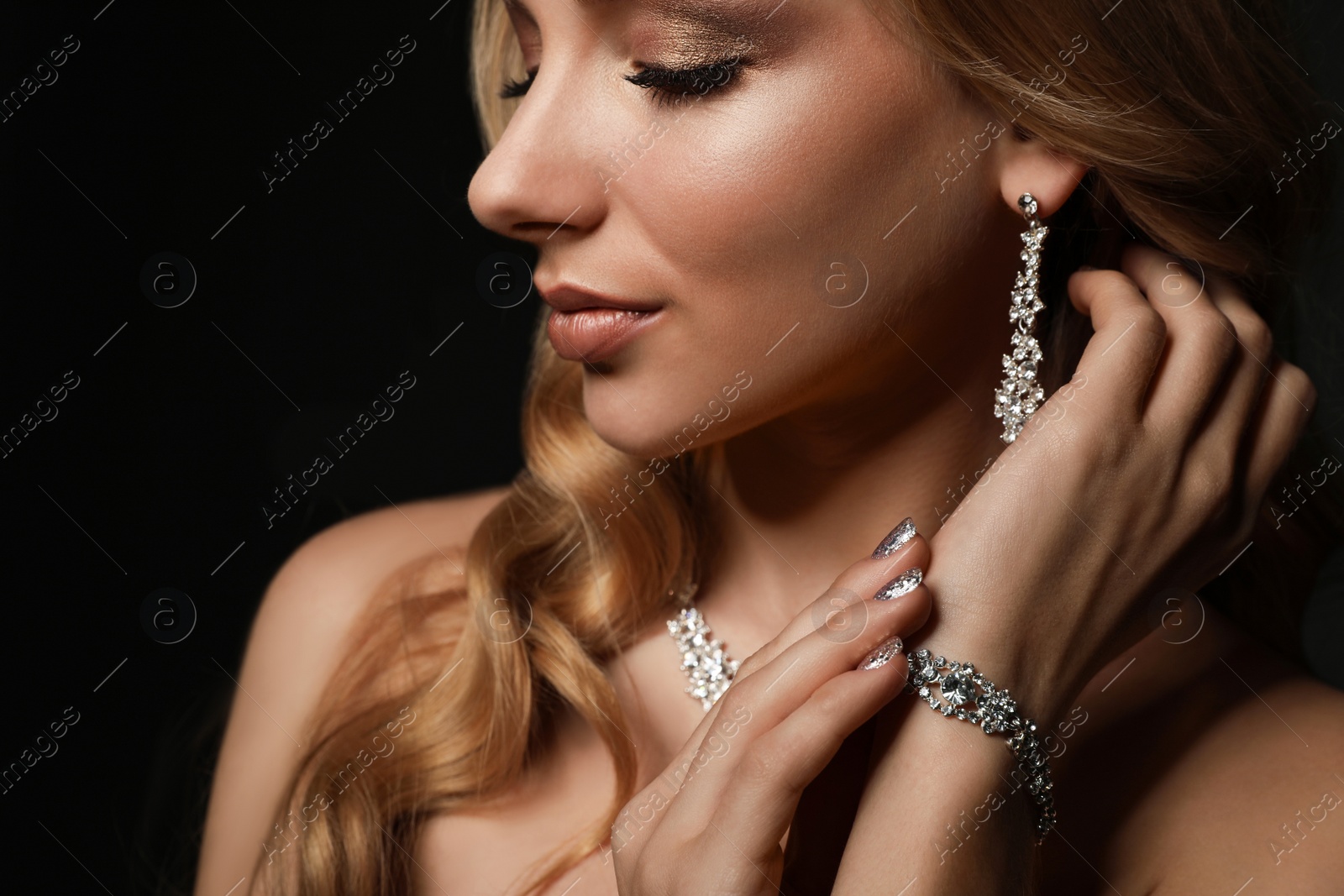 Photo of Beautiful young woman with elegant jewelry on dark background, closeup