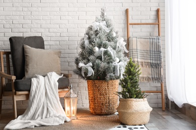 Stylish interior with beautiful Christmas tree near white brick wall