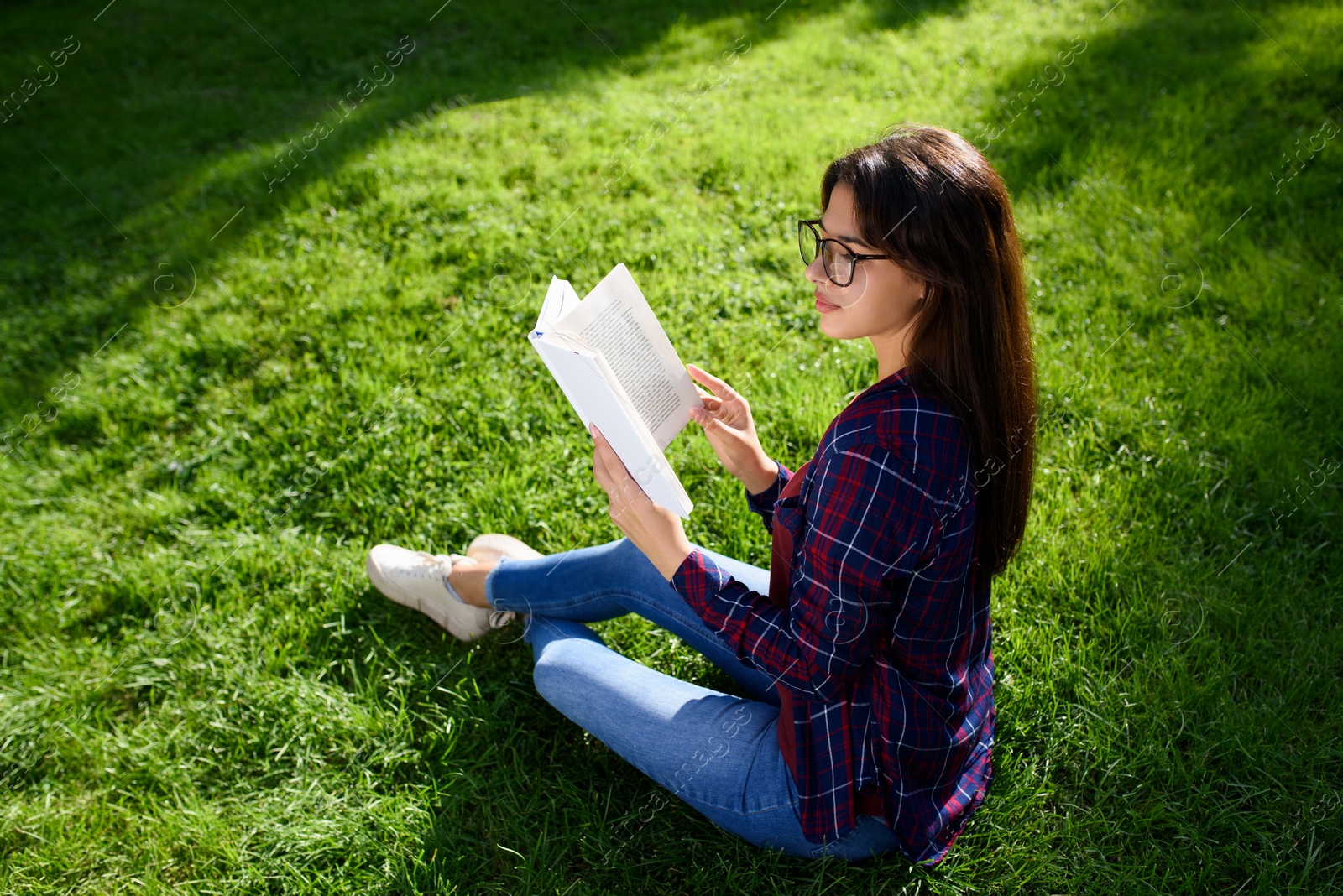 Photo of Young woman with book on green grass outdoors