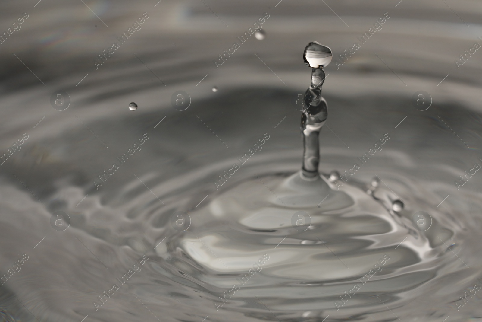 Photo of Splash of clear water with drops on grey background, closeup