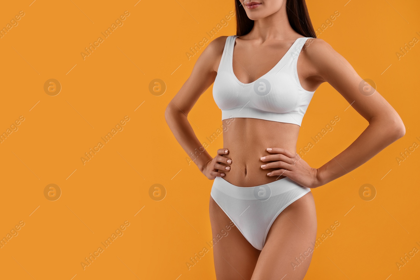 Photo of Young woman in stylish white bikini on orange background, closeup. Space for text