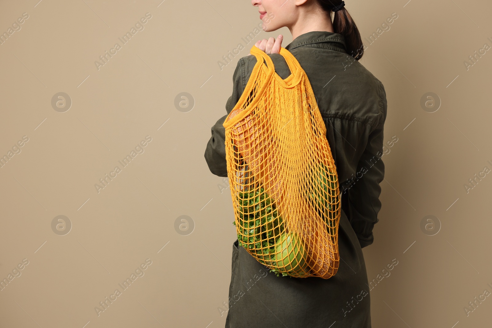 Photo of Woman with eco bag full of products on beige background, closeup. Space for text