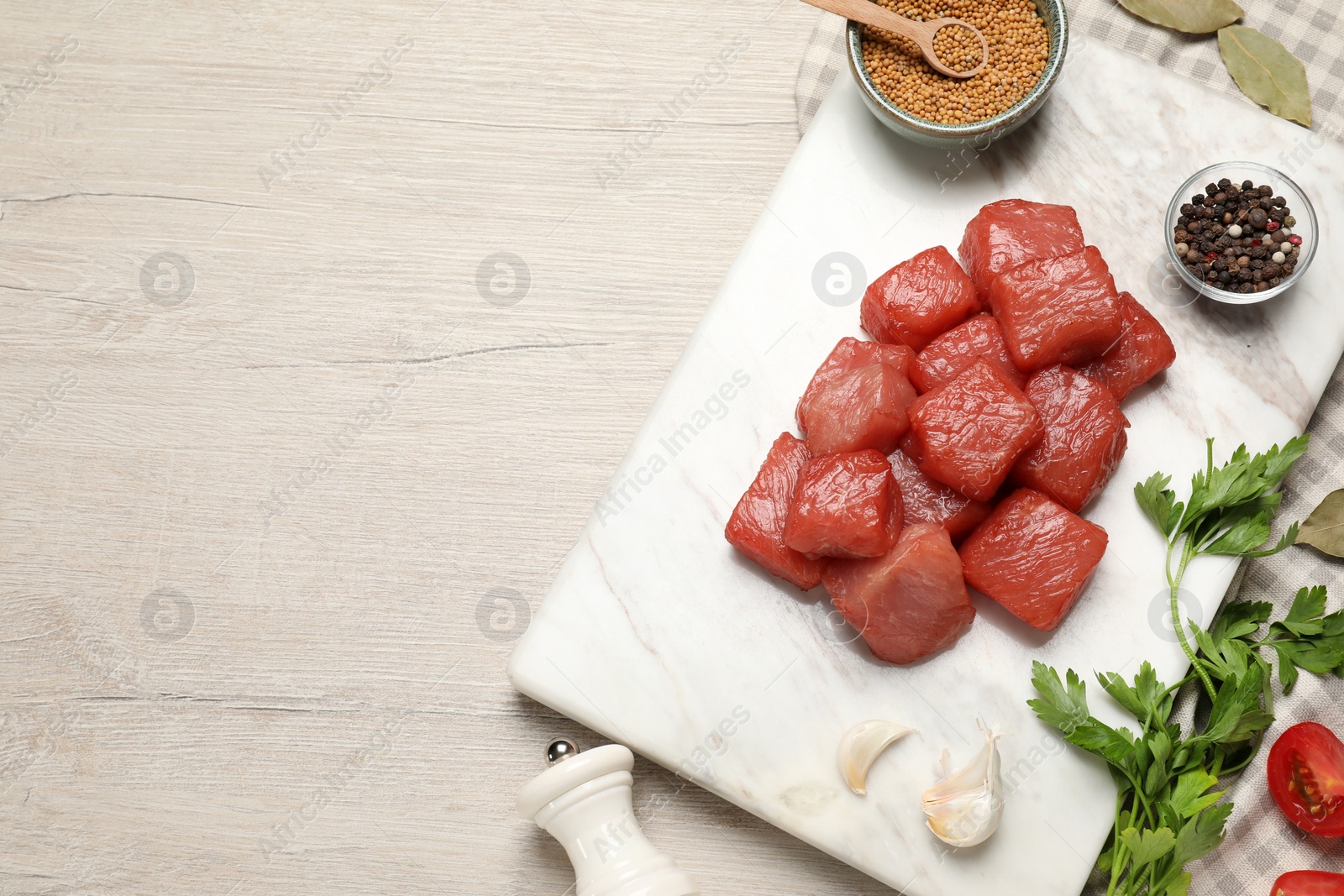 Photo of Raw beef meat and different ingredients for cooking delicious goulash on light wooden table, flat lay. Space for text