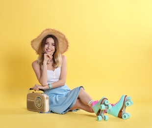 Young woman with roller skates and retro radio on color background