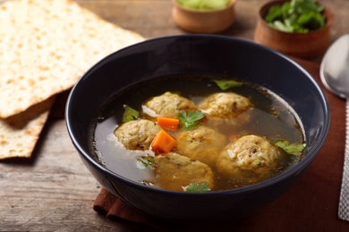 Photo of Bowl of Jewish matzoh balls soup on wooden table