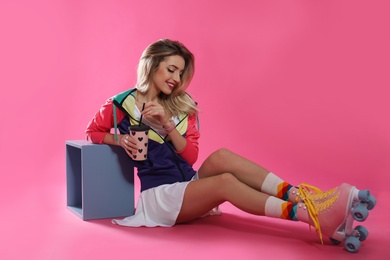 Photo of Young woman with retro roller skates and cup of drink on color background