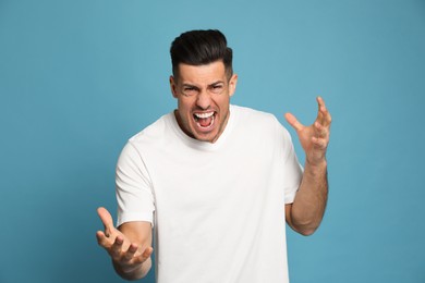 Photo of Angry man on turquoise background. Hate concept