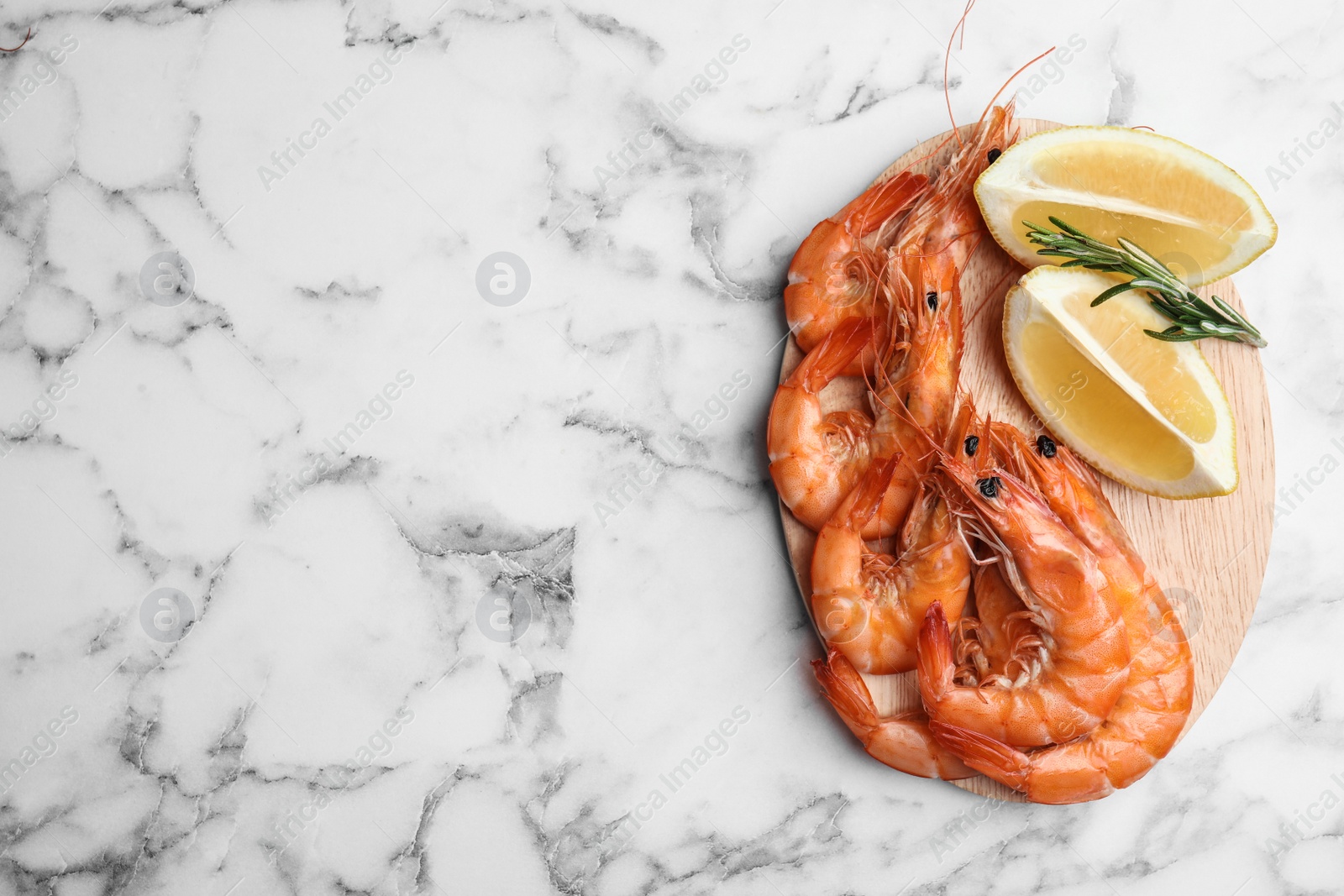 Photo of Delicious cooked shrimps with rosemary and lemon on white marble table, top view. Space for text