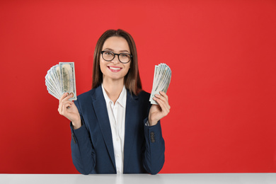 Photo of Young woman with money at table on crimson background