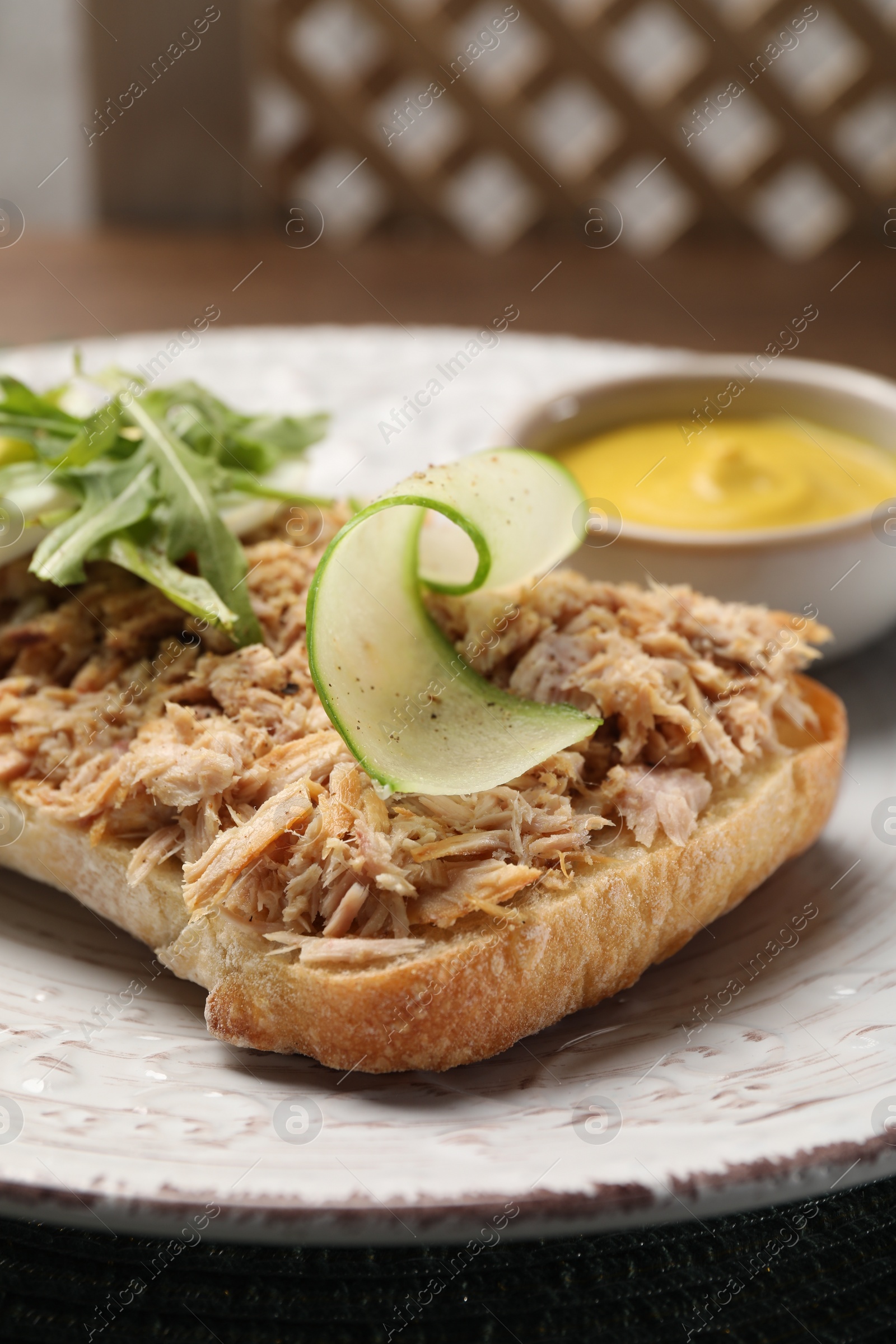 Photo of Delicious sandwich with tuna, boiled egg, vegetables and mustard sauce on white plate, closeup