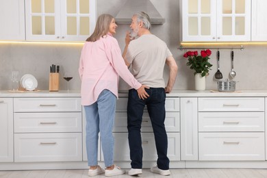 Affectionate senior couple spending time together in kitchen