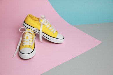 Photo of Pair of yellow classic old school sneakers on color background. Space for text