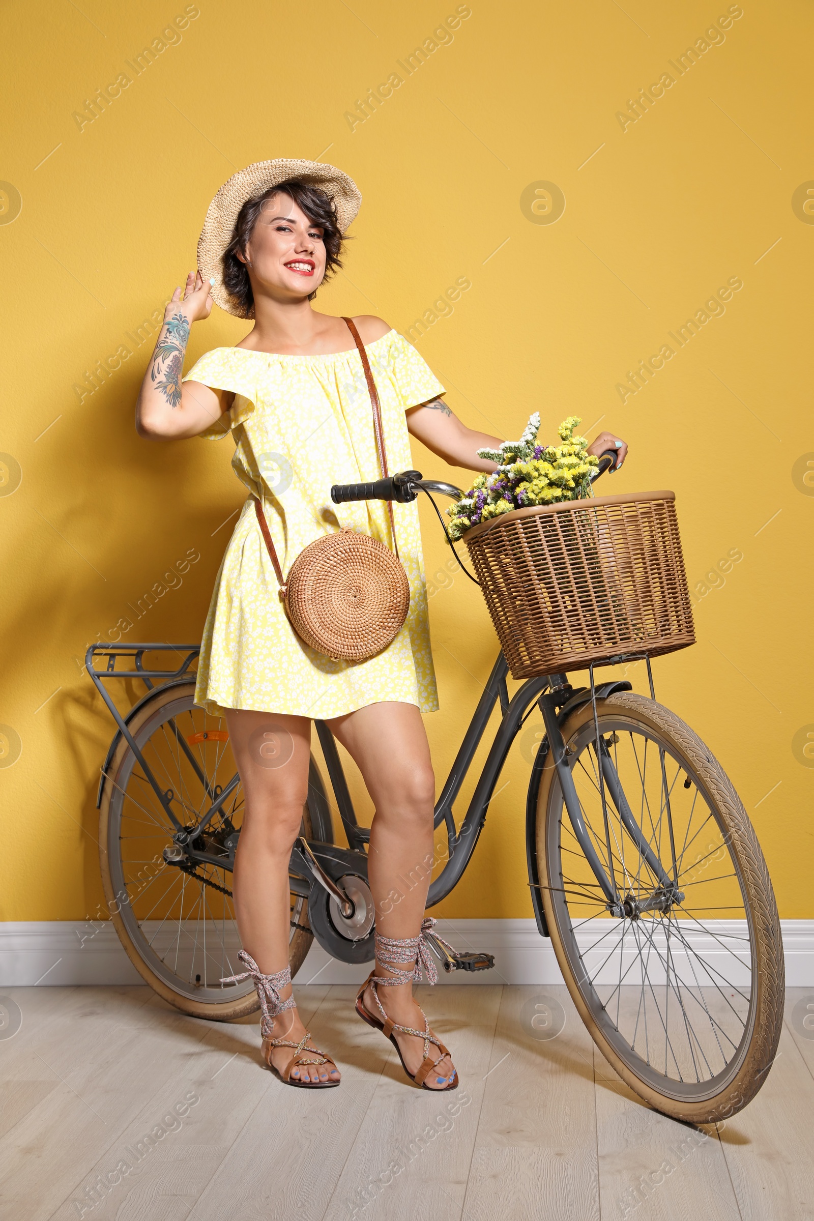 Photo of Portrait of beautiful young woman with bicycle near color wall