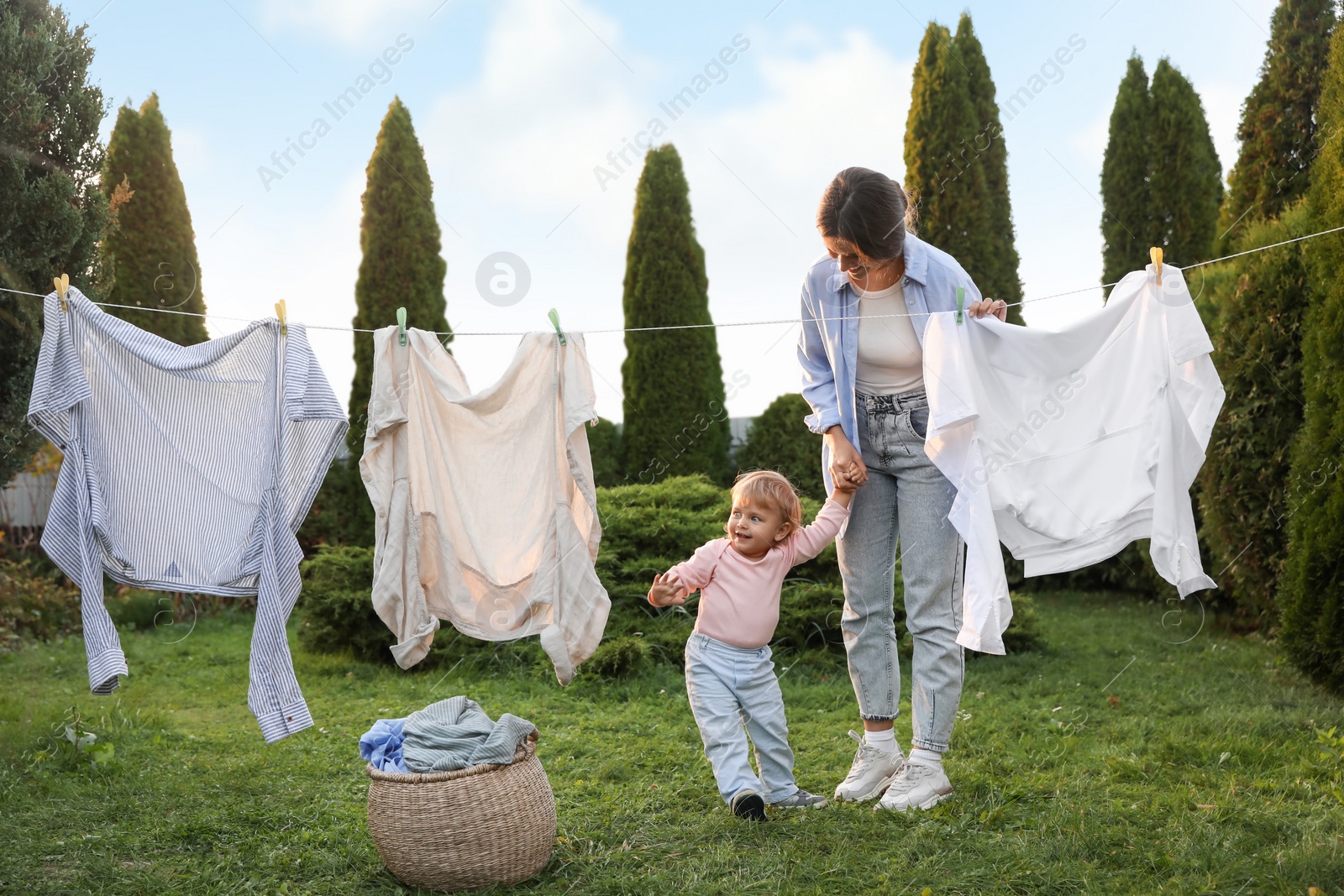Photo of Mother and daughter near washing line with drying clothes in backyard