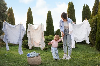 Mother and daughter near washing line with drying clothes in backyard