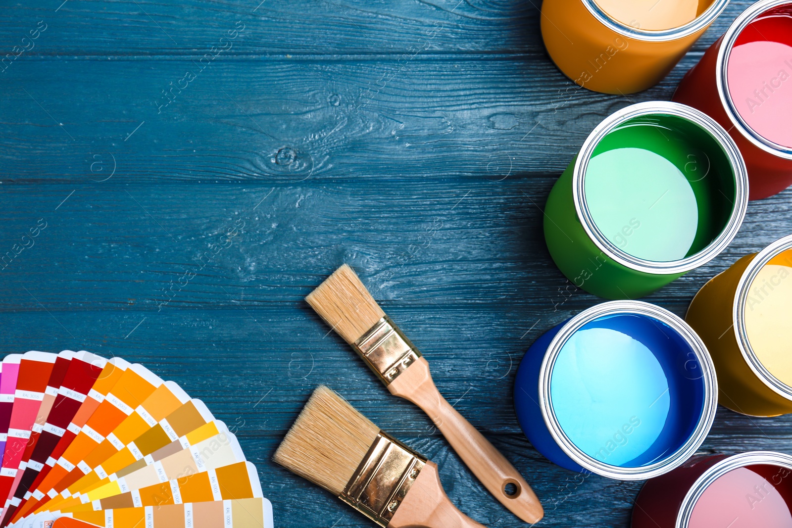 Photo of Flat lay composition with paint cans, brushes and color palette on wooden background. Space for text