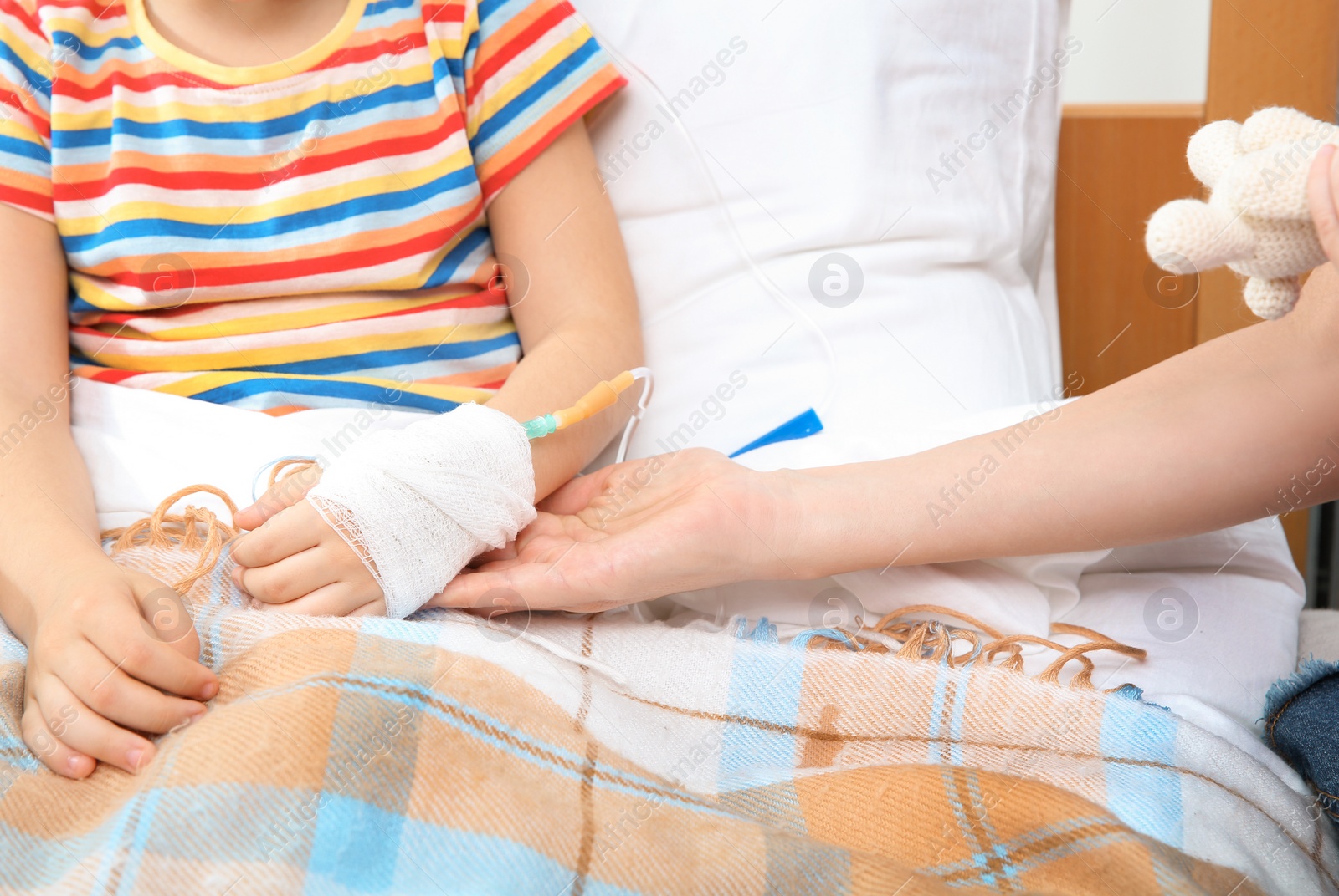 Photo of Doctor holding little child's hand with intravenous drip in hospital, closeup