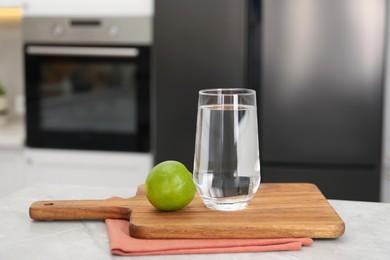 Photo of Filtered water in glass and lime on light table in kitchen