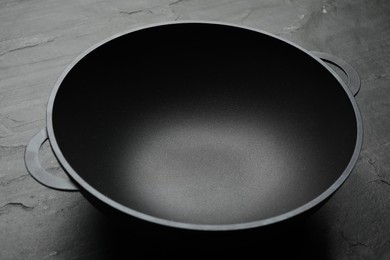 Photo of Empty iron wok on black slate table, closeup. Chinese cookware