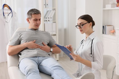 Photo of Gastroenterologist with clipboard consulting patient in clinic