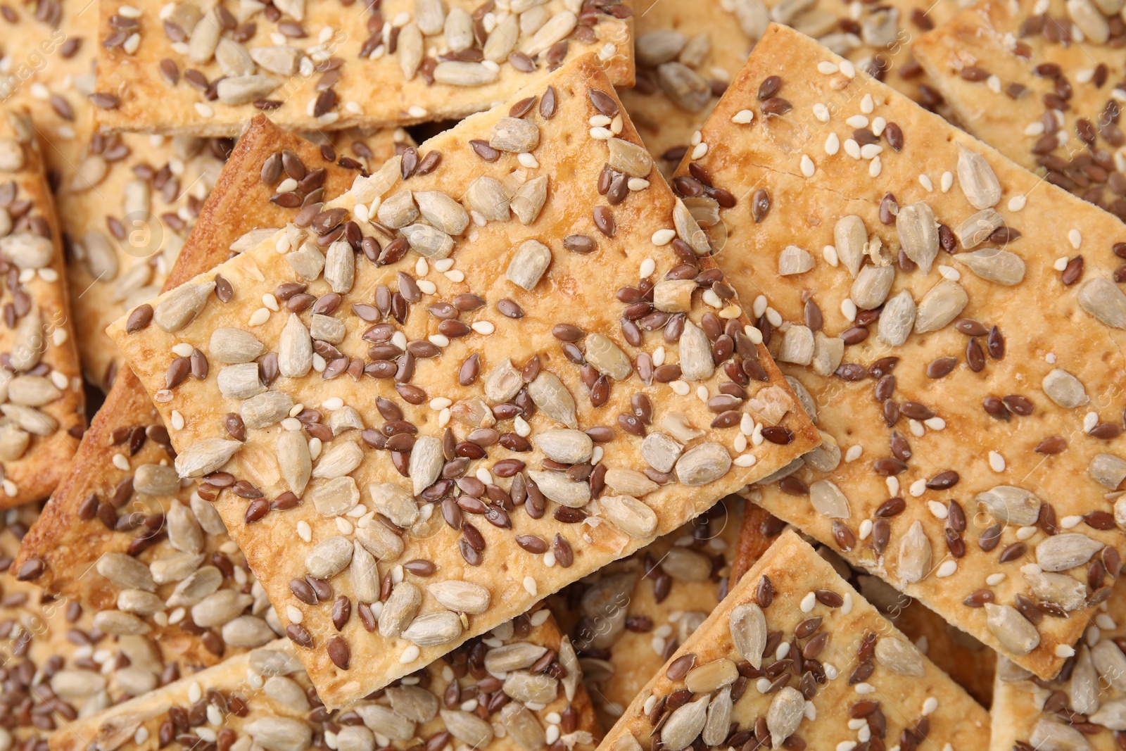 Photo of Cereal crackers with flax, sunflower and sesame seeds as background, closeup