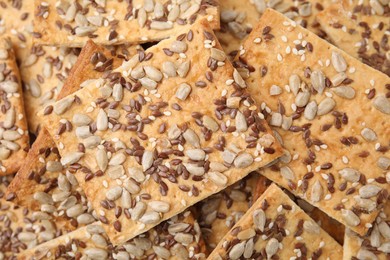 Photo of Cereal crackers with flax, sunflower and sesame seeds as background, closeup