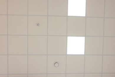 Photo of White ceiling with PVC tiles and lighting, bottom view