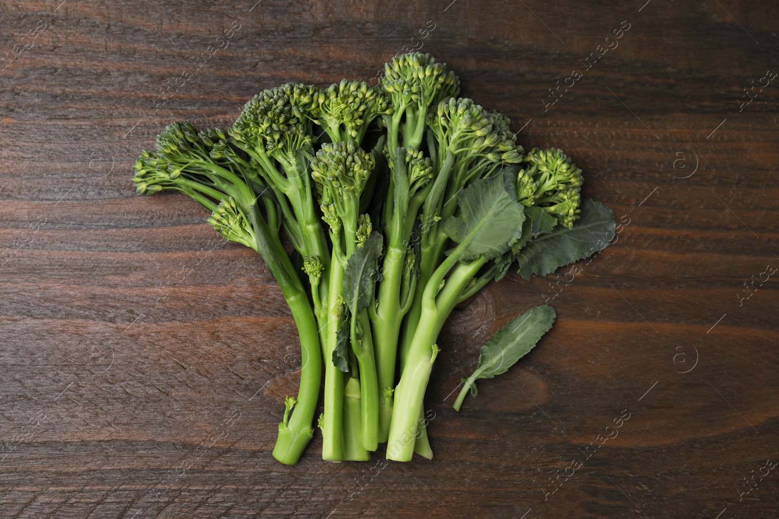 Photo of Fresh raw broccolini on wooden table, flat lay. Healthy food