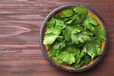 Photo of Fresh green parsley on wooden table, top view. Space for text