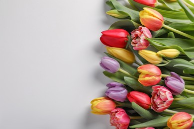 Photo of Beautiful tulips on light grey background, top view. Space for text