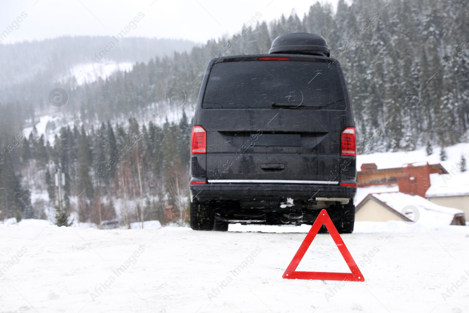 Photo of Emergency stop sign and broken car on snowy road in winter