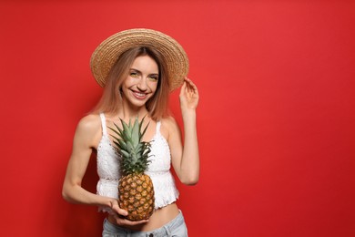 Young woman with fresh pineapple on red background, space for text. Exotic fruit