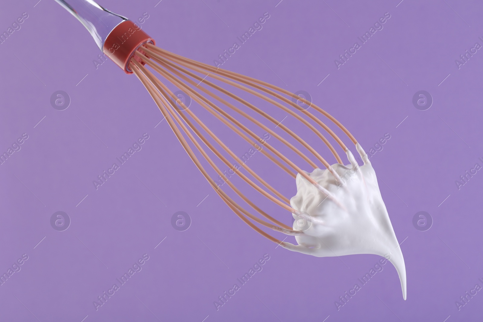 Photo of Whisk with whipped cream on violet background, closeup