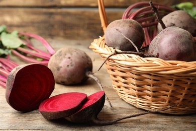 Photo of Cut and whole raw beets on wooden table