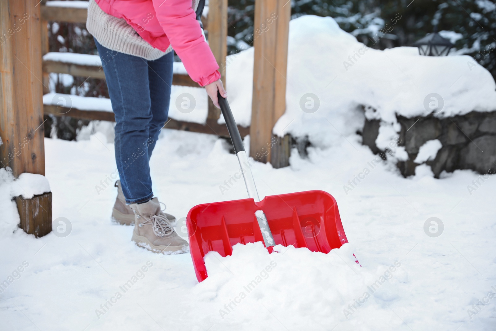 Photo of Woman cleaning snow with shovel outdoors on winter day, closeup