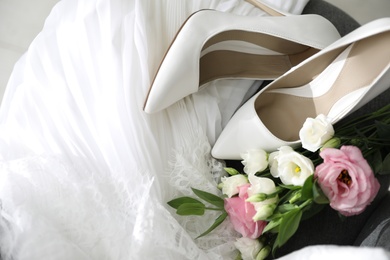 Pair of white high heel shoes, flowers and wedding dress, above view