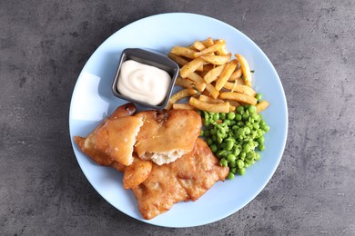 Photo of Tasty fish, chips, sauce and peas on grey table, top view