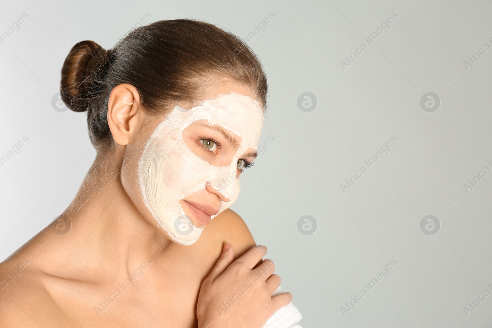 Photo of Beautiful woman with clay mask on her face against grey background. Space for text