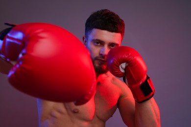 Photo of Man in boxing gloves fighting on color background