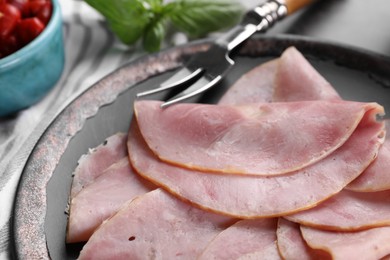 Photo of Tasty ham and carving fork on table, closeup view