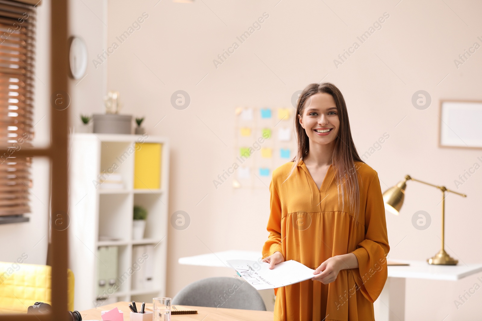 Photo of Young journalist with papers at workplace in office