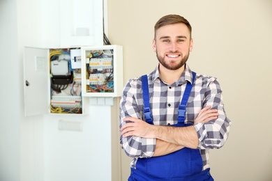 Male electrician standing near fuse board indoors